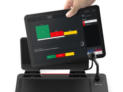 A hand placing a tablet into the docking station of the DICENTIS Multimedia device