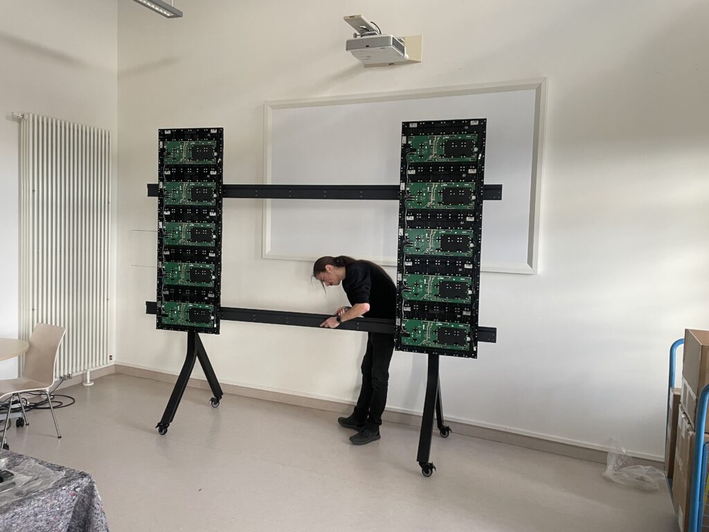 Technician mounting LED modules on a mobile stand in front of a wall